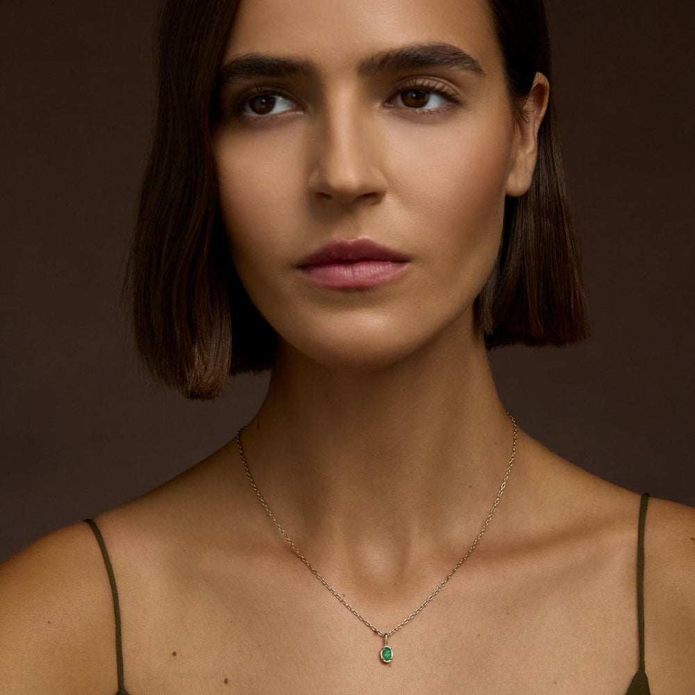 Woman wearing a chain necklace with a Emerald Pendant in 9kt Yellow Gold